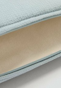 Svetle modrý texturovaný látkový obal s hladkým béžovým interiérem, s úhledným prošíváním podél okrajů.