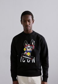 Black sweatshirt featuring a colorful graphic of a cartoon dog wearing goggles and a sports outfit, with "DSQUARED2 ICON" text beneath.