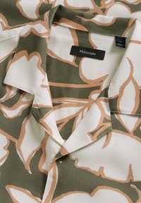 Short-sleeved shirt in a soft fabric featuring a green background with large white and peach floral patterns, and a pointed collar.