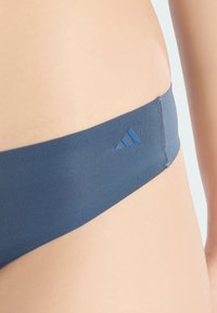 Marinblå sömlös bikiniunderkläder med en mjuk textur och elastisk midja, med en liten Adidas-logga i en ljusare blå nyans.