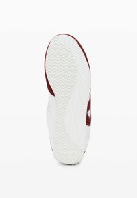 Talpa de pantof sport roșu și alb, cu un fund din cauciuc alb texturat, având un model ondulat și o parte superioară din suede roșu.