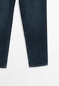 Donkerblauwe denim jeans met een rechte pasvorm, zichtbare stiksels en een standaard vijfzakkenontwerp. Gladde textuur en klassieke stijl.