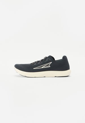 Chaussure de sport noire avec tige en maille, accents blancs, semelle rembourrée et bout arrondi. Présente un design à lacets et une silhouette épurée.
