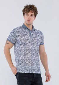 Polo a maniche corte di colore grigio chiaro con un motivo a rilievo, colletto scuro e pattina con bottoni. Il materiale sembra liscio e traspirante.