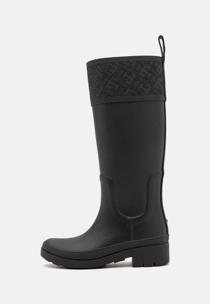 Botte de pluie en caoutchouc noir avec un bandeau supérieur noir à motifs, texture lisse, forme légèrement courbée et semelle plateforme basse texturée.
