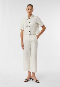 Linen blend two-piece outfit in off-white with vertical black stripes. Short-sleeved cropped shirt with two front pockets and wide-leg trousers.