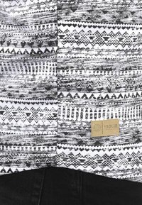Cotton shirt with a monochrome Tribal pattern in black and white. Features a small beige label with "ISOLID" text. Texture appears smooth.