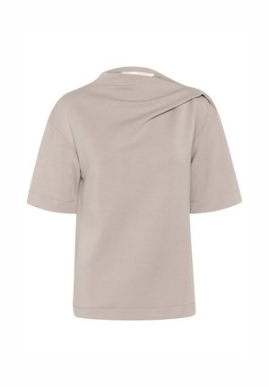 Maglietta a maniche corte color beige chiaro con una vestibilità comoda, dettaglio asimmetrico sulla spalla e una texture del tessuto morbida e liscia.