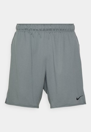 Lysegrå Nike-shorts med elastisk midjebånd, side- lommer og en svart logo nederst til venstre. Jevn, pustende stoff.