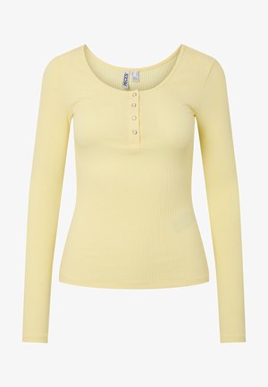 Svetlo rumena rebrasta majica z dolgimi rokavi, z okroglim izrezom in štirimi majhnimi dekorativnimi gumbi na sprednji odprtini.