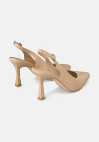 Tacones slingback de cuero beige con puntera afilada, un corte redondeado y un tacón cuadrado; cuentan con una correa delgada con una hebilla circular.