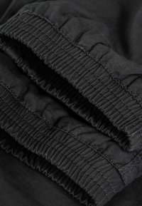 Close-up of black elastic waistband and gathered fabric on a pair of pants or shorts.