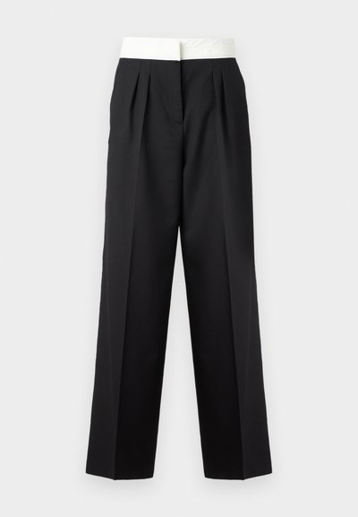 Pantaloni neri plissettati con una larga cintura bianca, caratterizzati da una linea dritta e una texture elegante per un look strutturato.