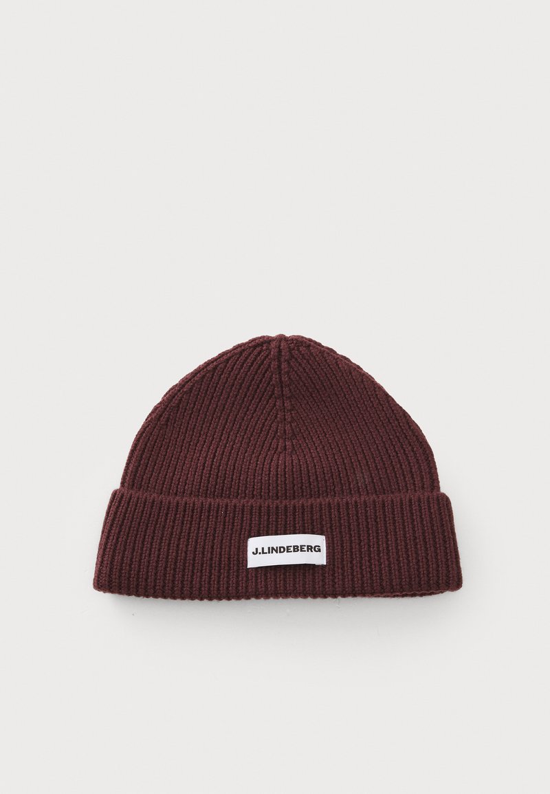 Burgundy knit beanie with ribbed texture, featuring a folded cuff and a white rectangular label with black text.