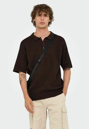 Brown short-sleeve polo shirt with a collar, two buttons, and a textured fabric. Paired with light beige cargo shorts and a black shoulder bag.
