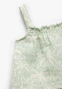 Vestido de algodón verde claro con tirantes finos, que presenta un corpiño fruncido y un patrón floral blanco. Textura suave, diseño casual.