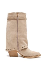 Botín de ante beige hasta el tobillo con punta afilada, cremallera lateral, tacón de madera y detalles con tachuelas a lo largo del dobladillo.