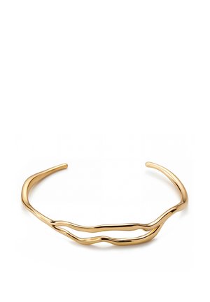 Avoin kultainen rannemansetti, jossa on kaksi epäsäännöllistä, aaltoilevaa nauhaa, muodostaen minimalistisen, modernin muotoilun.