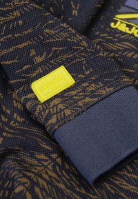 Marine sweatshirt met een textuurpatroon in goud, met een gele merklabel. De mouwen hebben een geribbelde afwerking voor een comfortabele pasvorm.