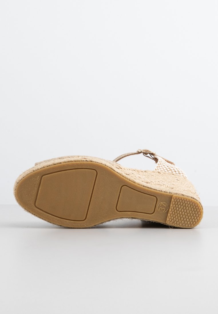 Beige Keilsandalette mit jutenumwickeltem Absatz, Gummisohle mit Profil und einem Knöchelriemen mit Schnalle, von der Sohle aus gezeigt.