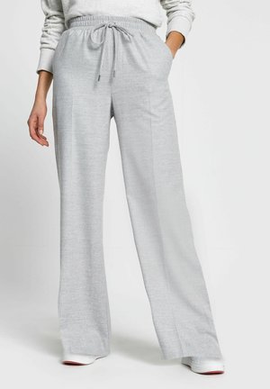 Person wearing light grey wide-leg pants with drawstring waist and side pockets, paired with white sneakers and light sweatshirt.