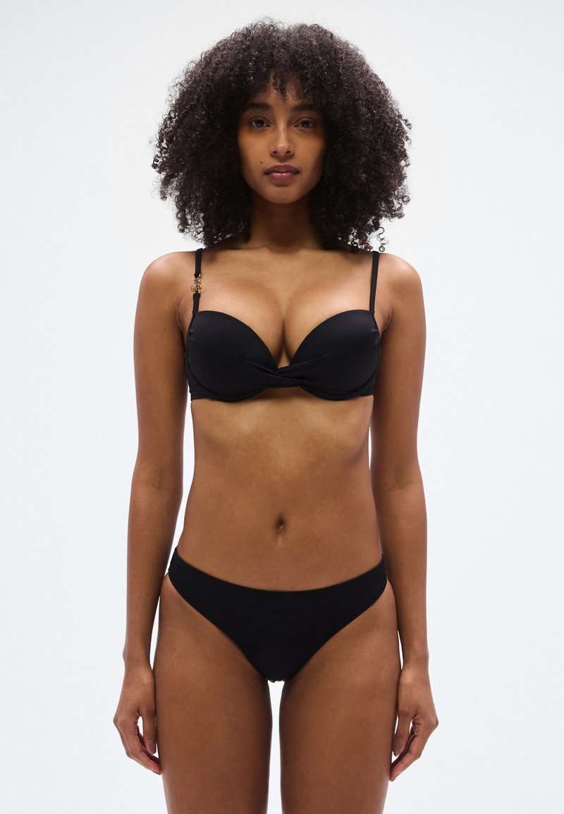 Μαύρο μπικίνι με επενδεδυμένο, στριφτό πάνω μέρος με ρυθμιζόμενους ιμάντες και κάτω μέρος με ελάχιστη κάλυψη. Λείο υλικό χωρίς ορατά σχέδια.