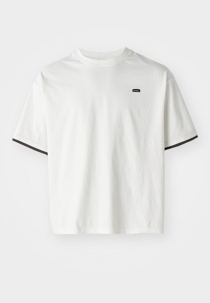 Witte katoenen t-shirt met een ronde hals, korte mouwen en zwarte accenten op de mouwranden. Heeft een klein zwart logo op de borst.