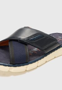 Ναυτικό μπλε σαγιονάρα με υφασμάτινο λουράκι textured και ελαστικές λεπτομέρειες. Διαθέτει παχύ στρώμα στην πατούσα και ελαφριά καουτσούκ σόλα.