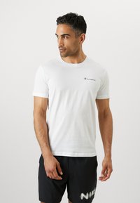 White cotton t-shirt featuring a small navy "Champion" logo on the chest. Classic crew neck and short sleeves. Simplistic design.