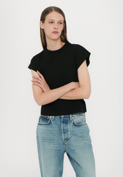 Black short-sleeve cropped t-shirt, made from soft cotton, paired with light blue high-waisted jeans featuring a faded wash and classic five-pocket design.