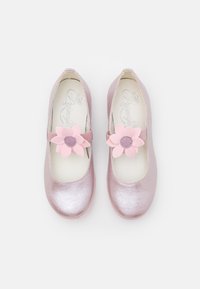 Ballerines métalliques roses avec une lanière, présentant de grandes fleurs roses en accent et un centre texturé. Finition lisse et design à bout rond.