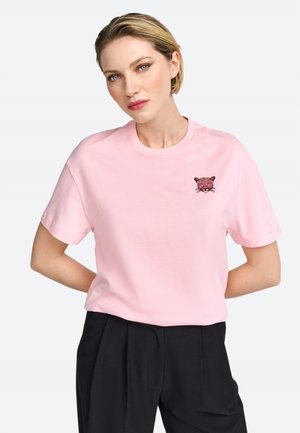 Camiseta de algodón rosa con un detallado rostro de jaguar bordado en el lado izquierdo del pecho. Tiene un cuello redondo clásico y mangas cortas.