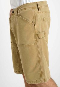 Shorts cargo en khaki en mélange de coton robuste, dotés de plusieurs poches et d'une coupe décontractée. Le tissu a une légère texture.