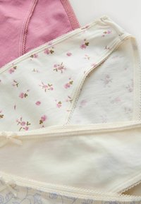 Kolm paari naiste puuvillast aluspesu tahkes roosas, valges roosilise lillemustriga ja valges väikese vibukujundusega on korralikult kihiti laotud.