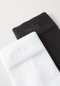 Baumwollmischungssocken, eine weiß und eine schwarz, mit geripptem Muster. Jede Socke hat ein dezentes Logo, das auf dem Bündchen gestickt ist. Weiches und langlebiges Design.