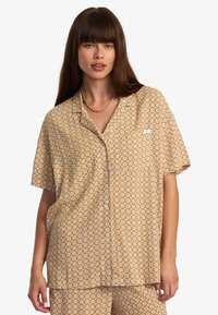 Chemise de pyjama à manches courtes et à boutons, en jaune moutarde avec un motif floral, dotée d'une poche et d'une coupe décontractée.