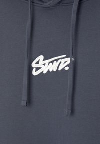 Námořnická mikina s bílým vyšitým logem "Stüssy". Má stahovací šňůrky a manžety s žebrovaným vzorem. Vyrobena z měkkého, strukturovaného materiálu z bavlněné směsi.