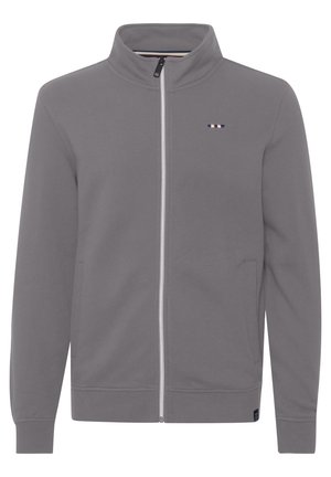 Pelēks kapucejams džemperis ar augstu apkakli, garām piedurknēm, sānu kabatām un mazu logotipu uz krūtīm. Mīksta auduma ar gludu tekstūru.