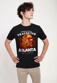 Camiseta de algodón negra con un diseño gráfico en naranja y blanco que incluye "Trackstar Atlanta Raceway" y una ilustración de una motocicleta.