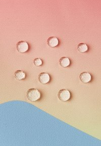 Gocce chiare disposte in modo irregolare su uno sfondo a gradiente testurizzato, che passa dal rosa al blu, mostrando forme circolari e riflessi.