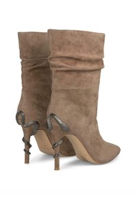 Stivaletti in suede taupe con design morbido, punta affusolata e accentuazione in metallo a forma di serpente sul tacco. Texture liscia e silhouette aderente.