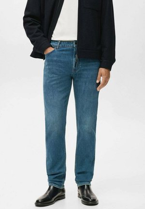Blauwe denim jeans met een rechte pijp, subtiele vervaging, vijf-pocket ontwerp, gecombineerd met zwarte leren laarzen en een marineblauwe jas.