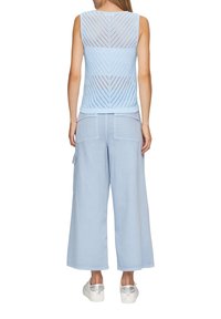 Jasnoniebieski dzianinowy top na ramiączkach w wzór zygzakowy, zestawiony z luźnymi, jasnoniebieskimi spodniami z bocznymi kieszeniami i elastycznym stanem.