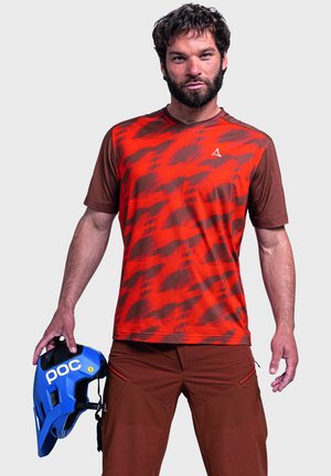 Rotes und braunes Kurzarmhemd mit einem gemusterten Design; begleitet von einem blauen Helm mit 'poc'-Logo. Das Material scheint leicht zu sein.
