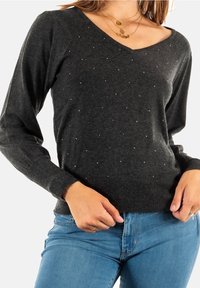 Dunkelgrauer gestrickter Pullover mit V-Ausschnitt, langen Ärmeln und verstreuten Strassverzierungen auf der Vorderseite. Figurbetonter Schnitt mit gerippten Bündchen.