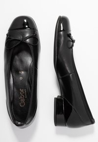 Black leather ballet flats featuring a glossy toe cap, bow detail, and low block heel. Smooth texture with stitched accents.