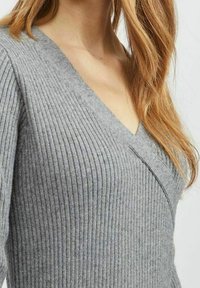 Maglione grigio a coste con design a V. Realizzato in morbido tessuto a maglia di spessore medio con accenti di texture verticale.