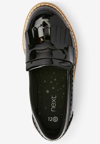 Chaussure en cuir verni noir avec un design à franges et du matériel décoratif. Bout arrondi et semelle contrastante couleur tan. Doublée de tissu foncé avec des étoiles.