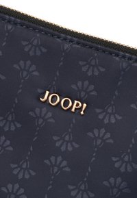 Navy zippered pouch made of textured fabric with subtle flower patterns. Features a gold "JOOP!" logo accent on the front.