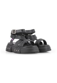 Sandalias de plataforma negras con una suela gruesa, que cuentan con múltiples correas entrelazadas y un cierre de hebilla lateral. Textura suave con acentos plateados.